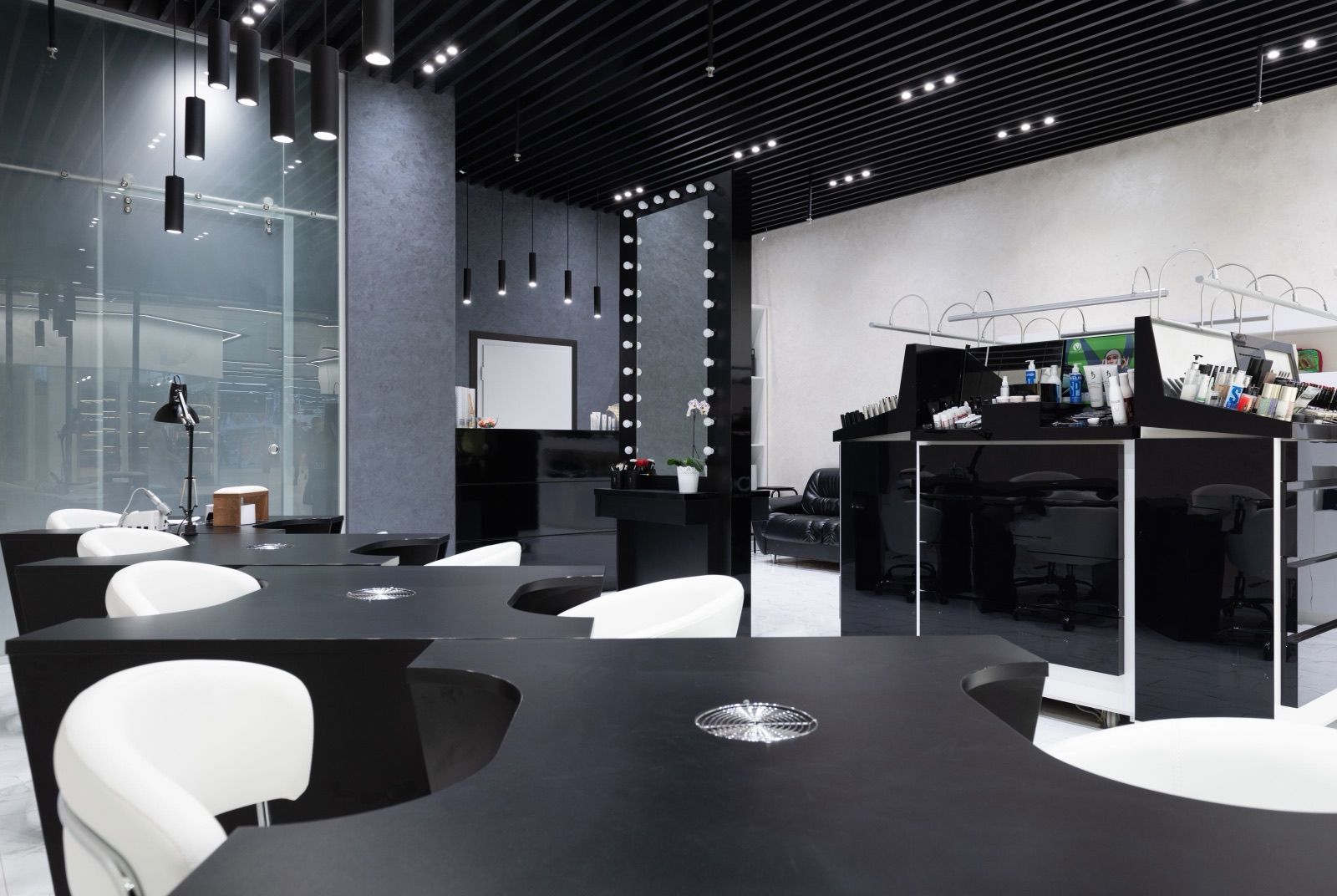 Modern nail salon interior with manicure stations and lit mirrors