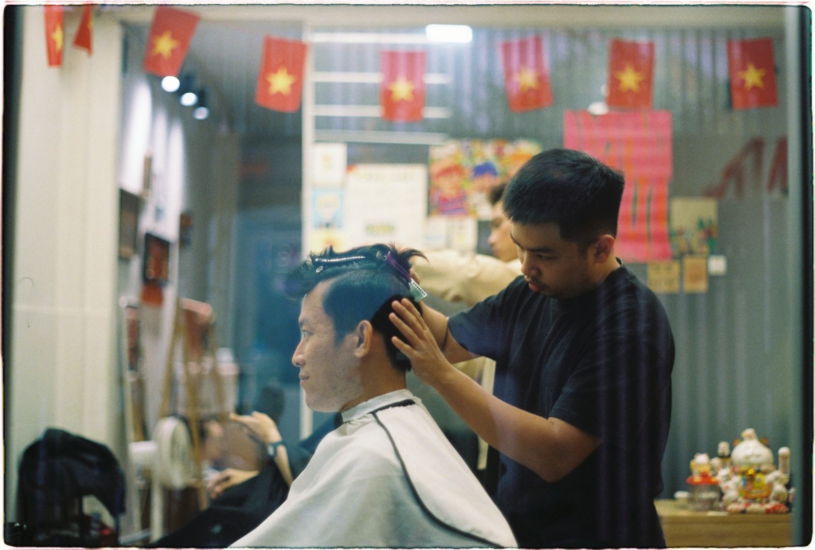 A barber giving a client a haircut in a busy shop