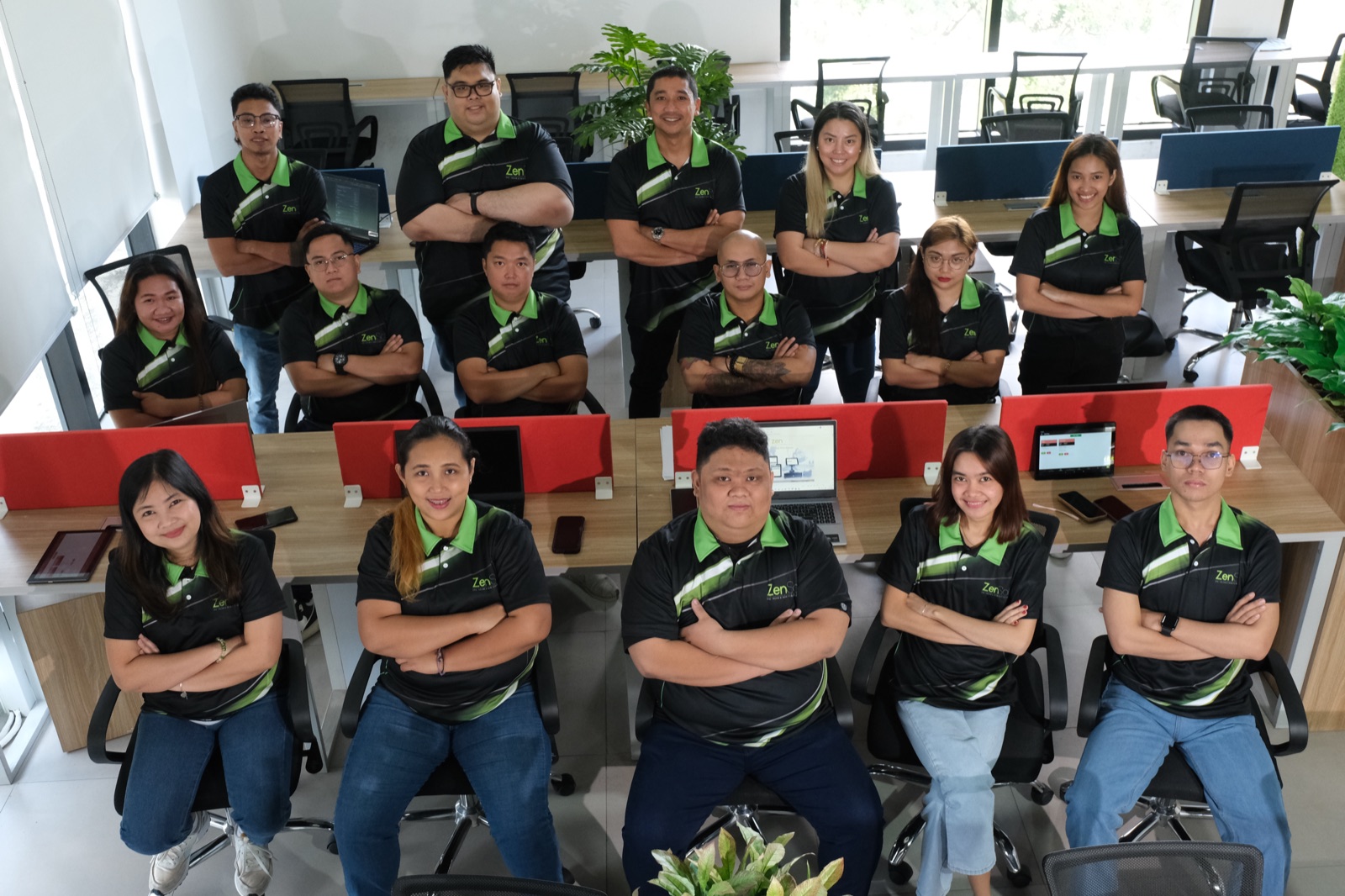 The ZenSoft team at their workstations, arms folded, looking up at the camera
