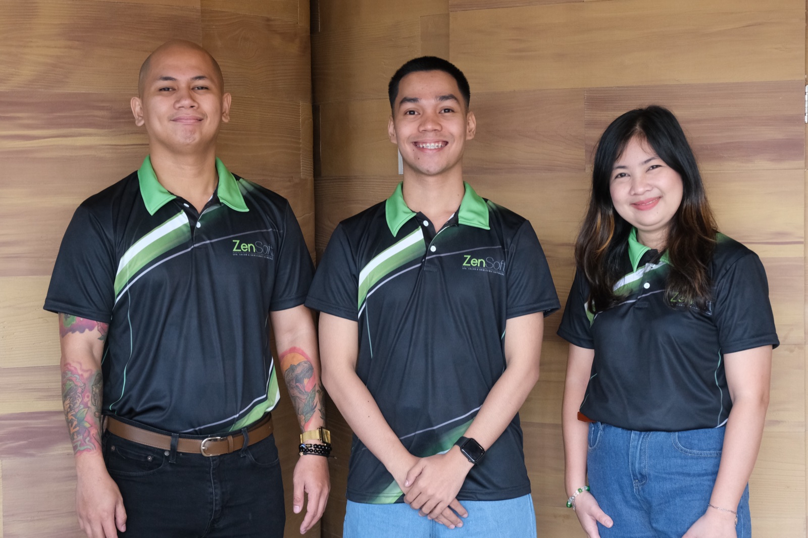 Three ZenSoft team members standing together against the office wood panel wall