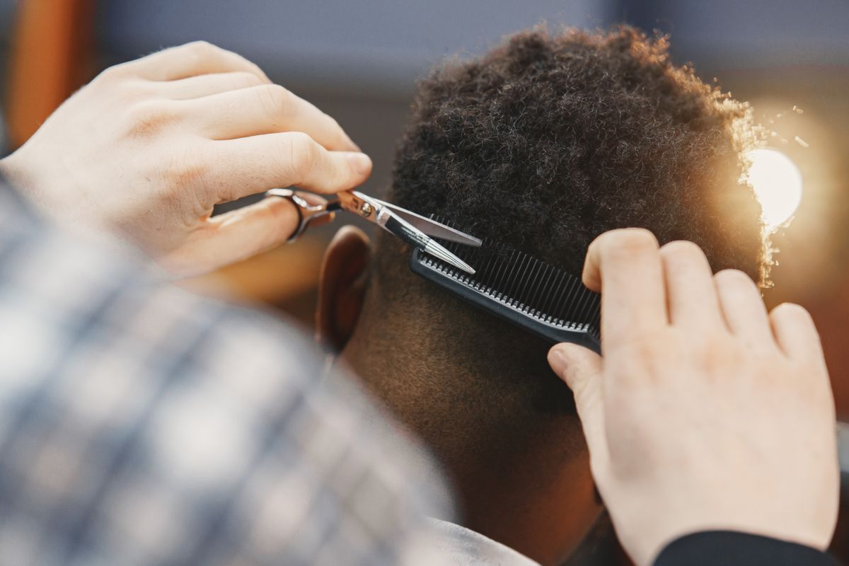 Barber cutting a client’s hair with scissors and comb